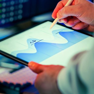 Professional analyzing data chart on a tablet with stylus in an office setting.